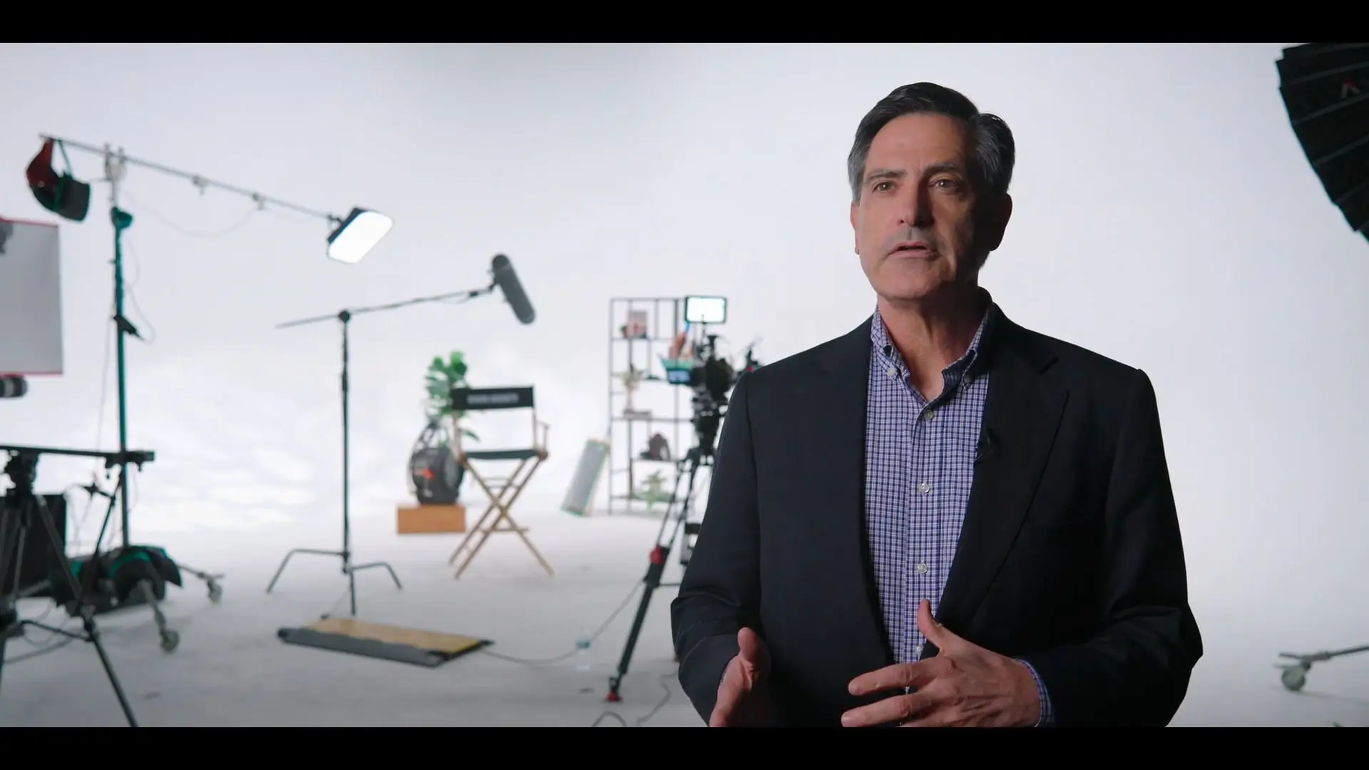 Man speaking during an interview, dressed in a suit jacket, standing in a well-lit room.